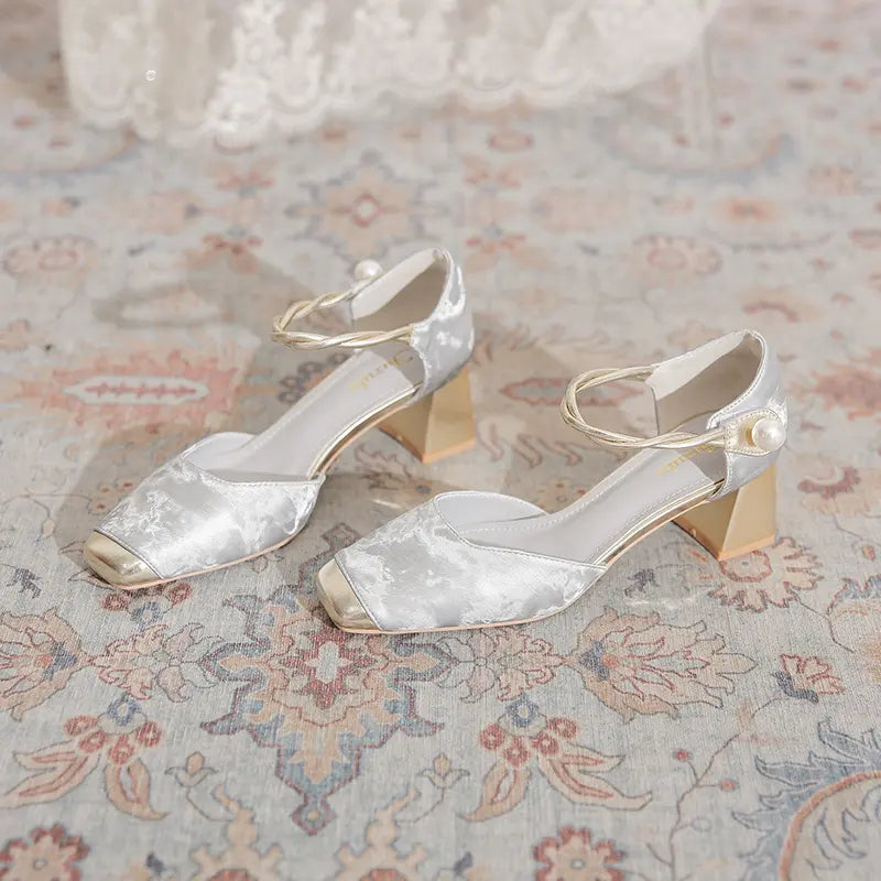 Elegant Silver Mist Chunky Heel Sandals featuring a square toe with gold metallic cap, a braided ankle strap adorned with a faux pearl, and a geometric block heel.