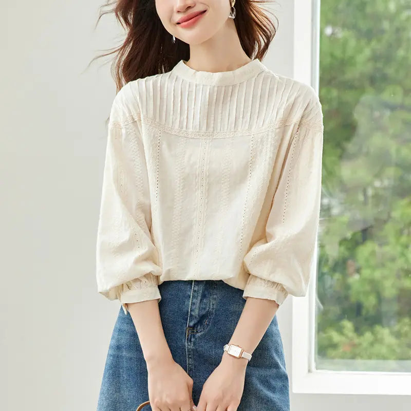 Elegant off-white embroidered cotton blouse with vintage lace yoke, gathered round neck, and voluminous bishop sleeves, worn by a model tucked into a denim skirt.