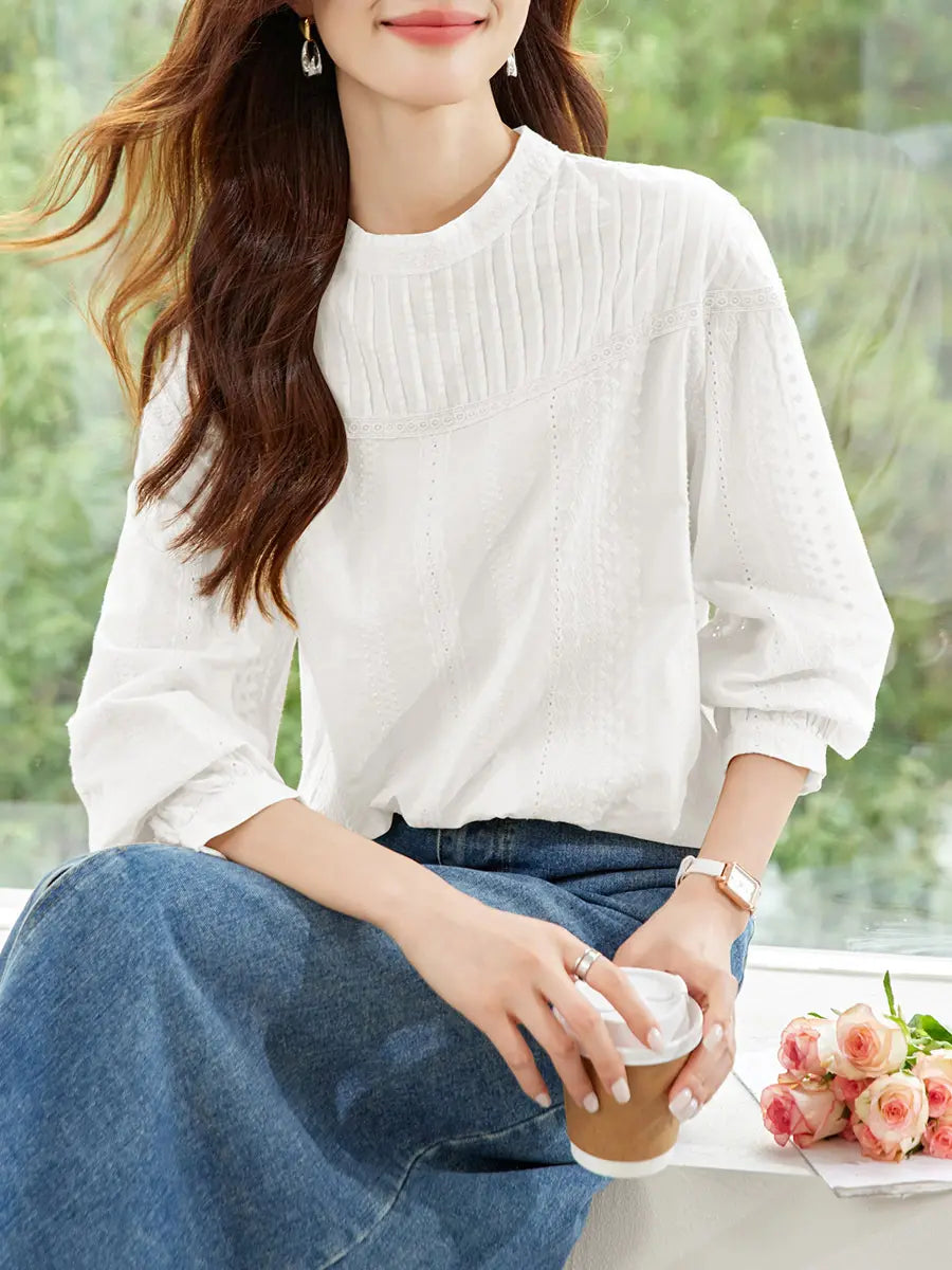 Woman wearing an elegant off-white embroidered cotton blouse featuring a delicate lace yoke, gathered round neckline, and voluminous bishop sleeves, styled with a denim skirt.