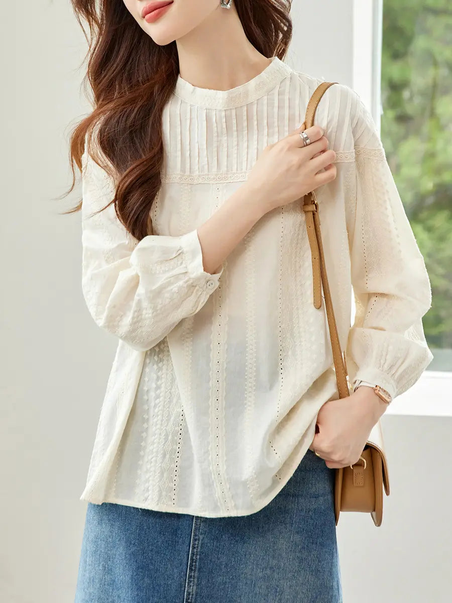 A woman models an elegant off-white embroidered cotton blouse with a lace yoke, gathered round neckline, and voluminous bishop sleeves, paired with a denim skirt and a crossbody bag.