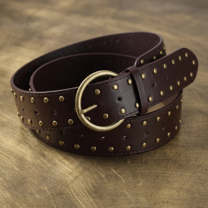 Wide punk-inspired belt made of dark PU leather, adorned with uniform antique brass studs and featuring a D-ring pin buckle.