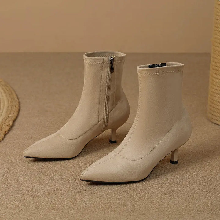 Taupe beige suede-like ankle boots with pointed toes, slender stiletto heels, and inner side zippers, shown from the front.