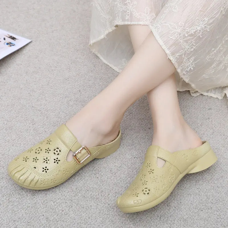 Light khaki textured synthetic mules with embossed geometric pattern, round toe, and adjustable gold buckle strap worn by a model in a lacy dress.