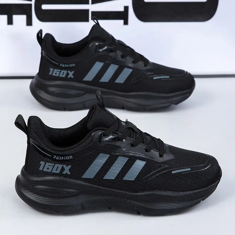 Pair of black Trovik low-top athletic sneakers shown from the side with a breathable mesh upper, chunky sole, and reflective grey three-stripe detail.