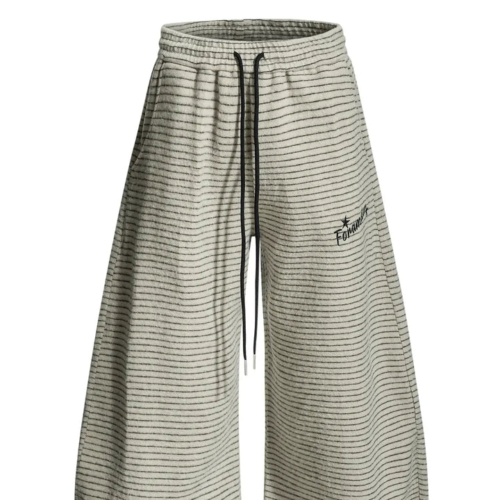 Beige unisex retro wide leg trousers featuring fine horizontal stripes, a high drawstring waist, and embroidered hip detail.