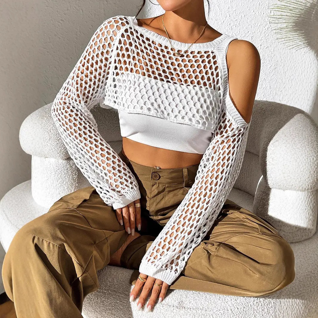 White Veridia open-knit crochet crop top with cold-shoulder detail, styled on a model with a white tank and cargo pants in a chic interior setting.