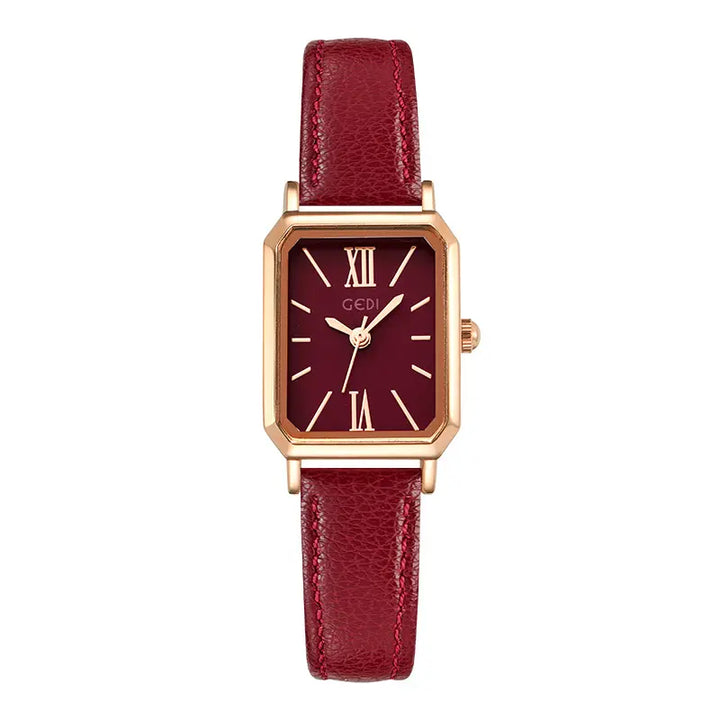 Rose gold-tone rectangular watch with a deep burgundy dial, featuring Roman numeral markers at XII, I, VI, XI, and dauphine hands. It is fitted with a red faux leather strap with white contrast stitching and a rose gold pin buckle.