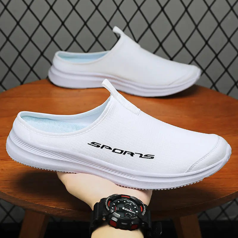 Men's white Vesklo slip-on mules with black 'SPORTS' logo on the side, held by a hand to showcase breathable textile upper and tan sculpted sole.