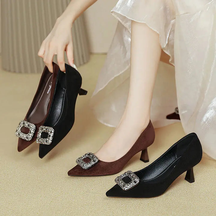 Elegant Vesryn pointed-toe court shoes in black and brown suede, adorned with a square crystal buckle and sculpted flared heel, shown on a neutral studio background.