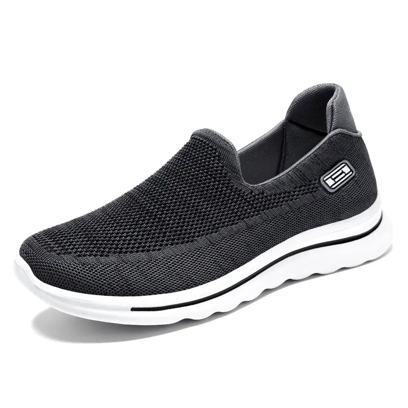 Black Veyla Comfort Knit Trainers slip-on sneaker for unisex wear, featuring a breathable mesh upper, cushioned white EVA sole with a black accent line, and a rounded toe.