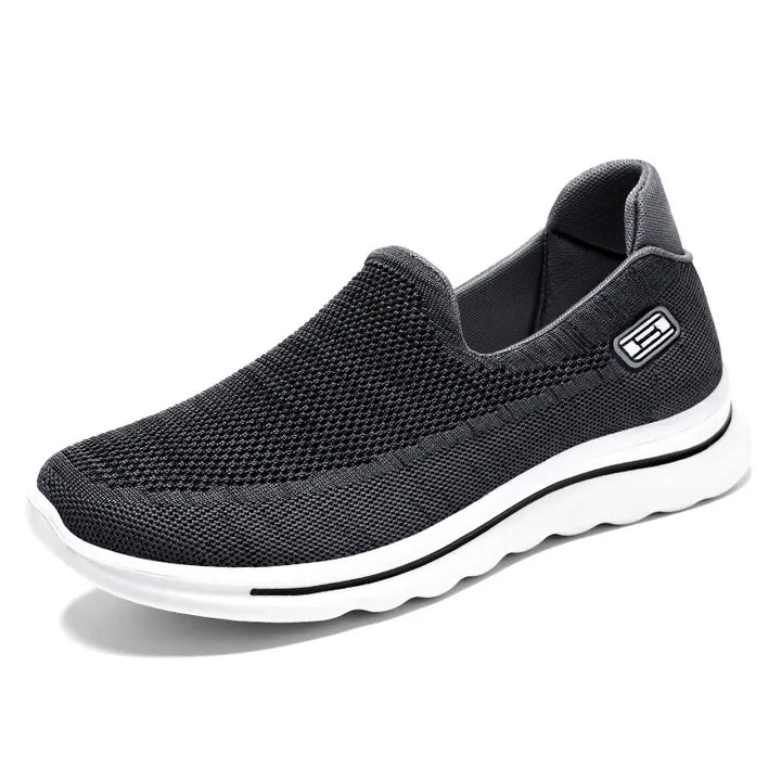 Black Veyla Comfort Knit Trainers slip-on sneaker for unisex wear, featuring a breathable mesh upper, cushioned white EVA sole with a black accent line, and a rounded toe.