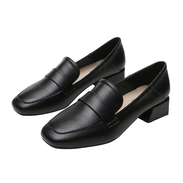 Pair of black faux leather loafers with a square toe, decorative vamp strap, and a stable block heel, shown from a front-three-quarter angle.