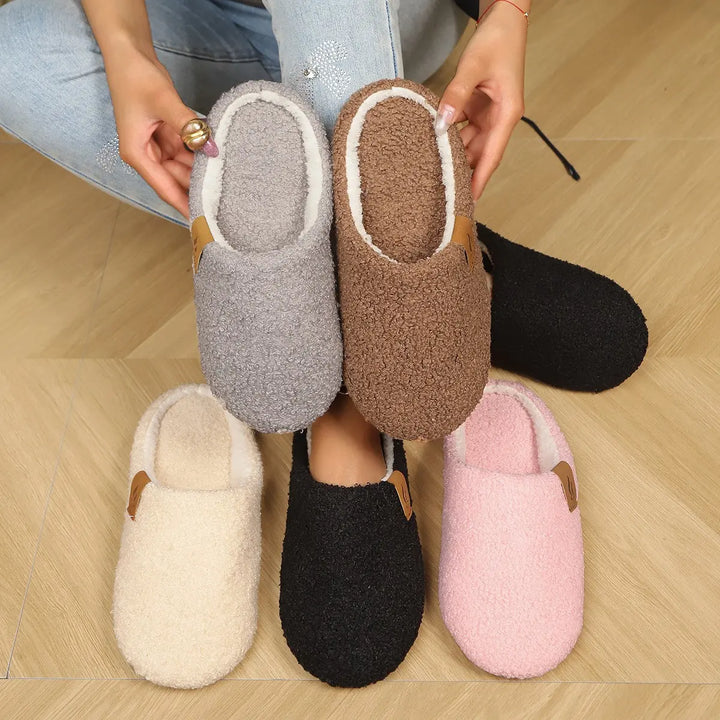 Collection of Vyrra plush indoor slippers in multiple colors including black, warm coffee, charcoal grey, cream beige, and blush pink, showcasing their cozy clog style from a top-down view.