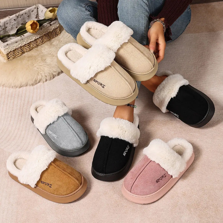 A collection of Vyxen plush faux fur lined mule slippers in various colors like dusty rose, black, grey, khaki, and brown, arranged artistically on a carpeted floor with a person&
