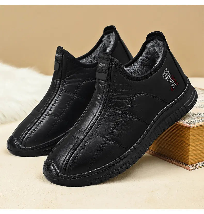 Black quilted synthetic leather slip-on winter boots for men, featuring plush faux fur lining, elasticated side gores, and a durable lugged rubber sole, shown from a three-quarter angle.
