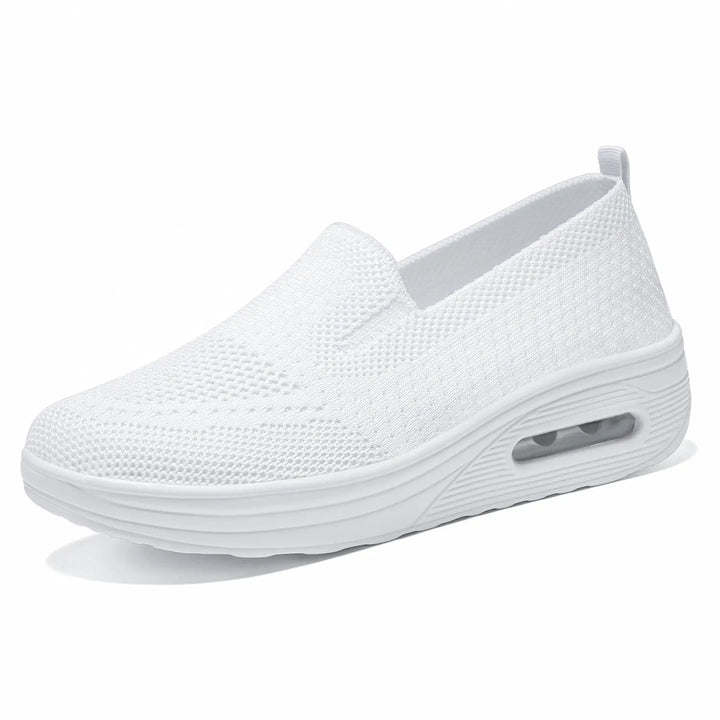 Front three-quarter view of a white Xylos breathable knit slip-on sneaker featuring a visible air cushion sole and a round toe.