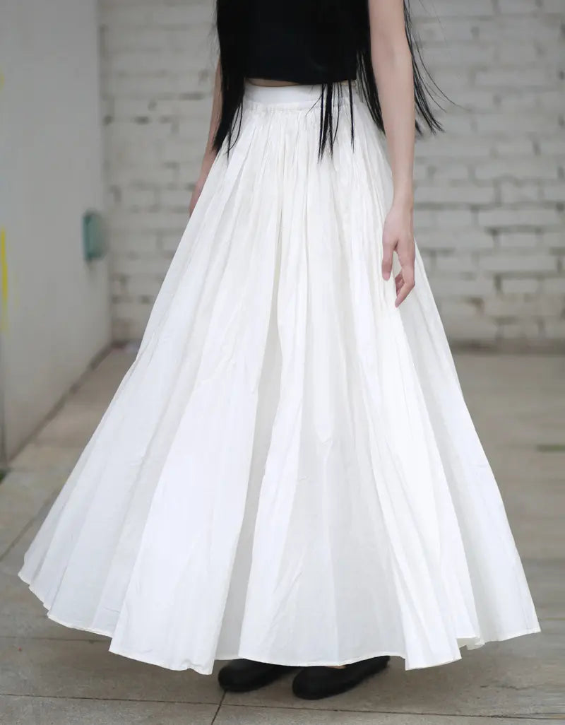 Voluminous white pure cotton maxi skirt worn by a model, featuring an elasticated waistband and a sweeping, flared A-line silhouette with a full hem.