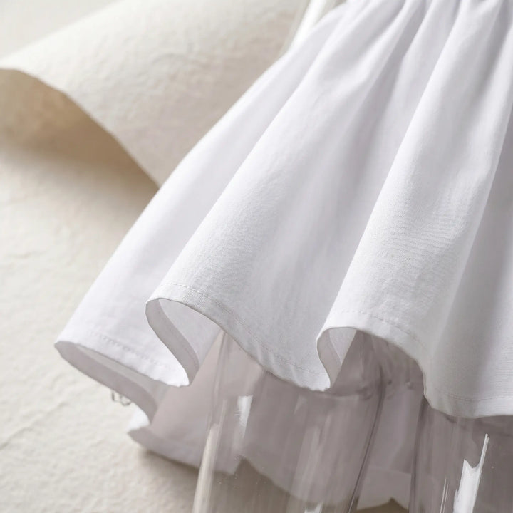 Close-up view of the voluminous, gathered bubble hem on a white mini dress, showcasing its textured fabric and playful volume.