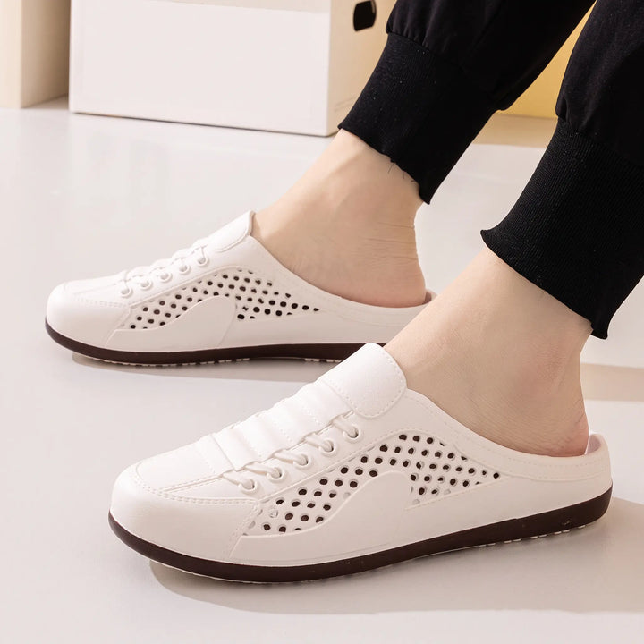 White breathable slip-on mule clogs with perforated design, worn on feet with black trousers, showcasing "FASHION" and "VIP" text detail.