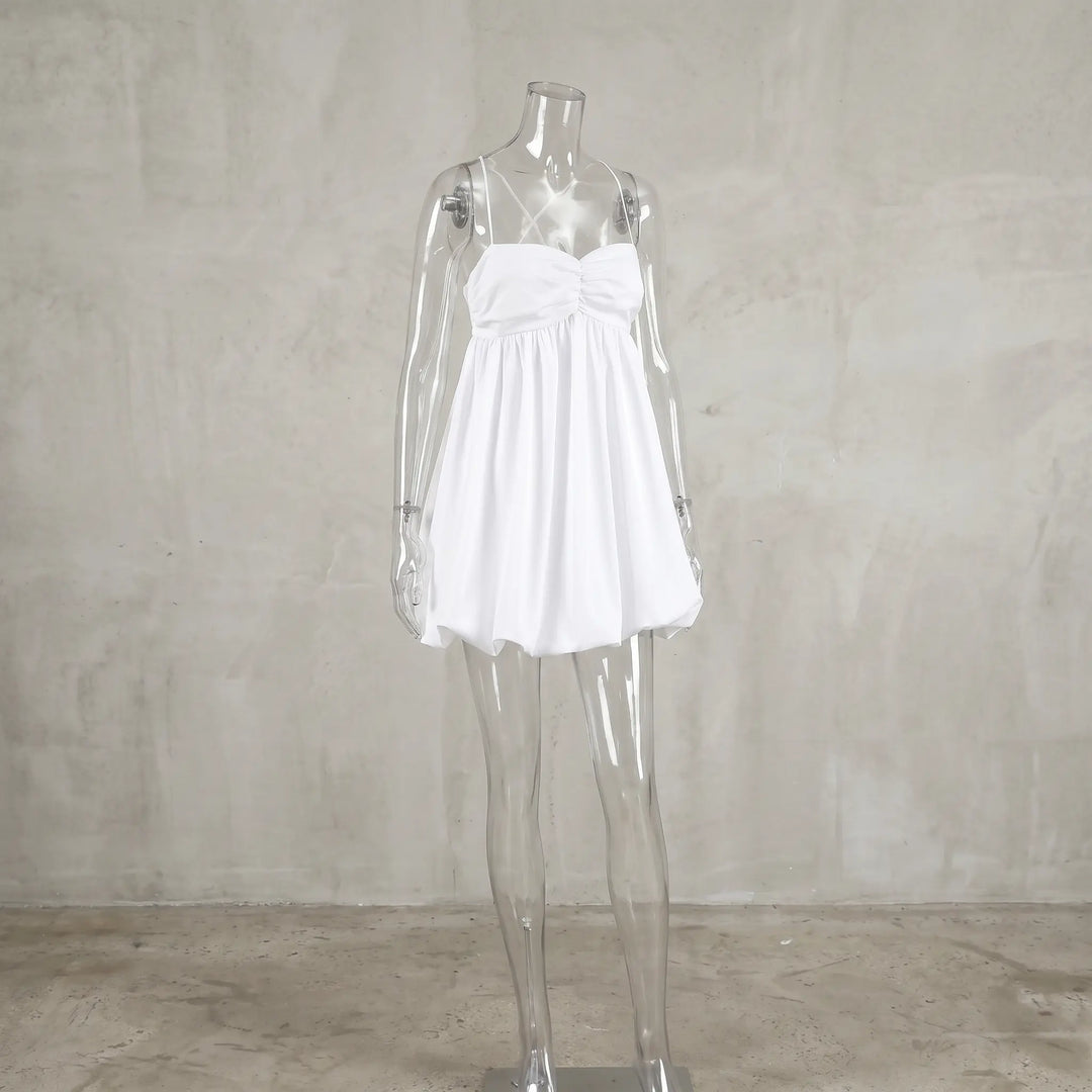 White ruched halterneck mini dress with a voluminous bubble hem, displayed on a mannequin against a textured studio background.