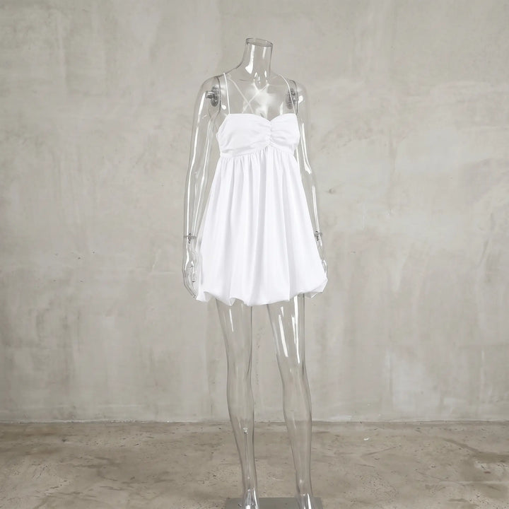 White ruched halterneck mini dress with a voluminous bubble hem, displayed on a mannequin against a textured studio background.