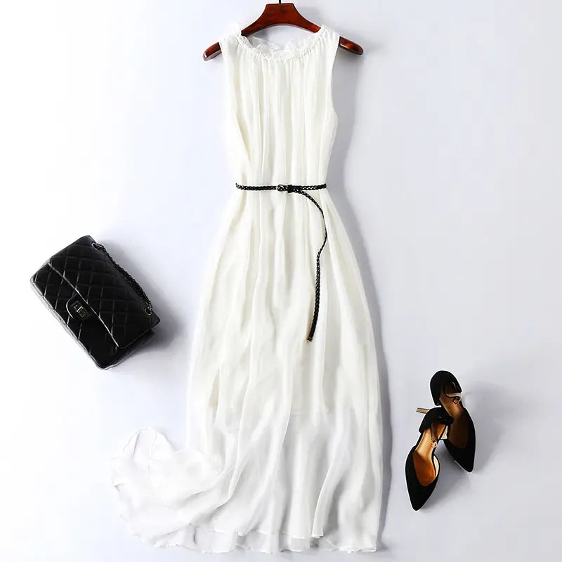 White pure silk sleeveless midi slip dress styled with a black braided belt and gold buckle, shown with a black quilted handbag and black high heels.