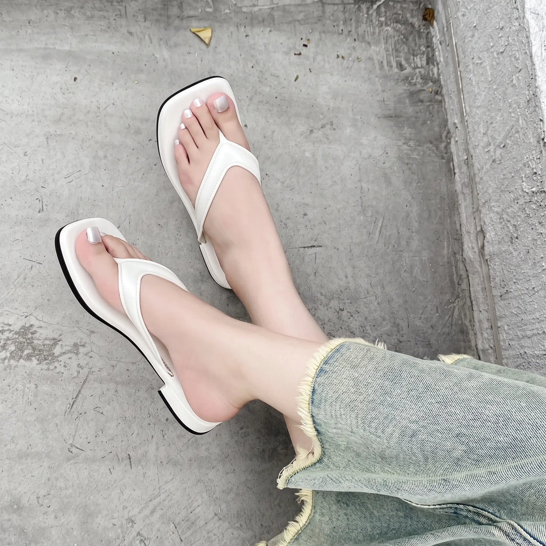 Lifestyle shot of white square-toe thong sandals worn by a person with cropped jeans, showing the comfortable design and summer fashion appeal.
