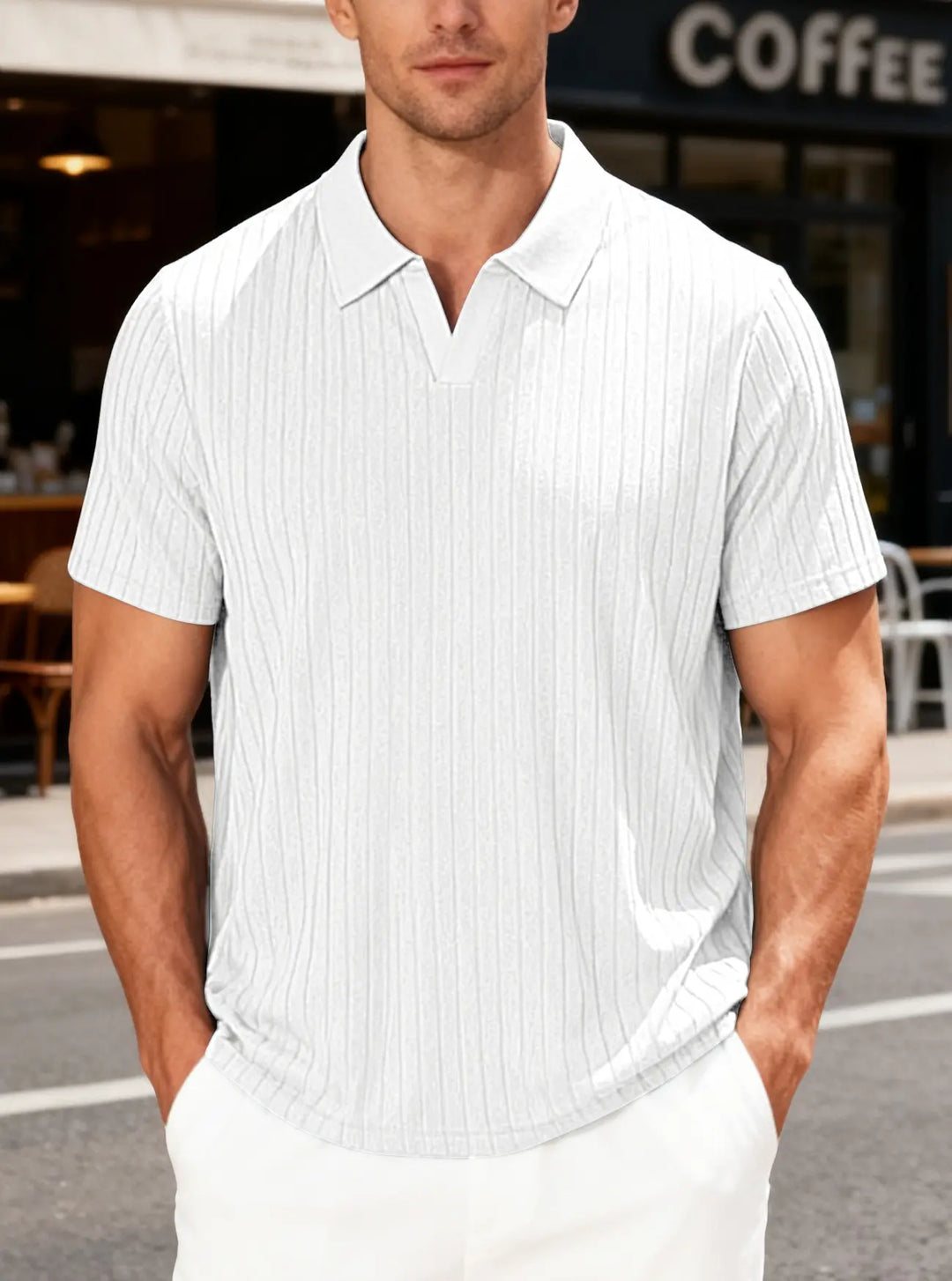A man models a white textured knit polo shirt with short sleeves and a deep V-neck collar, featuring fine vertical ribbing for a breathable summer style in an outdoor setting.