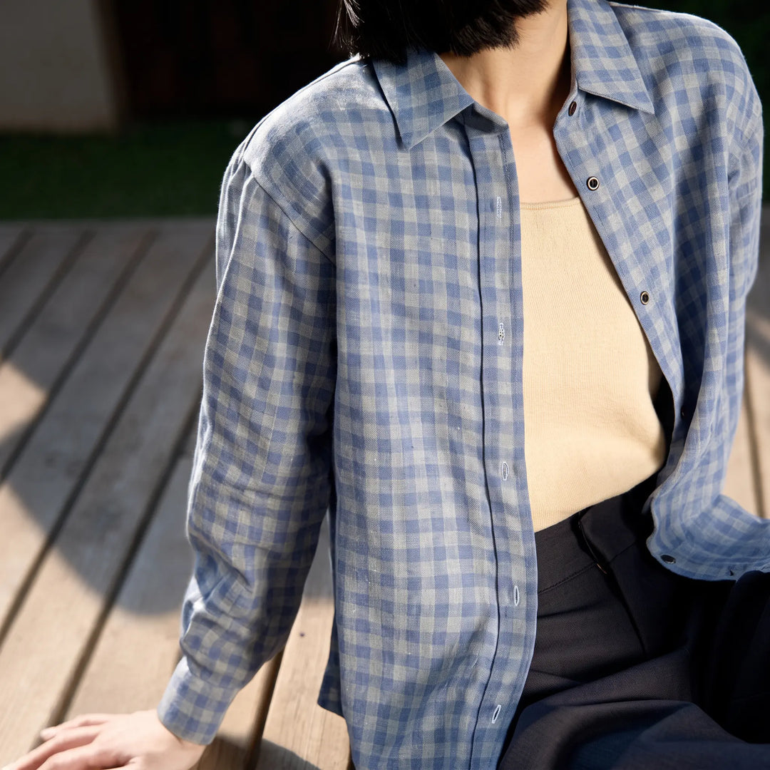 A woman wearing a relaxed-fit, blue and grey brushed cotton plaid button-down shirt with a POLO collar, styled casually on a wooden deck.