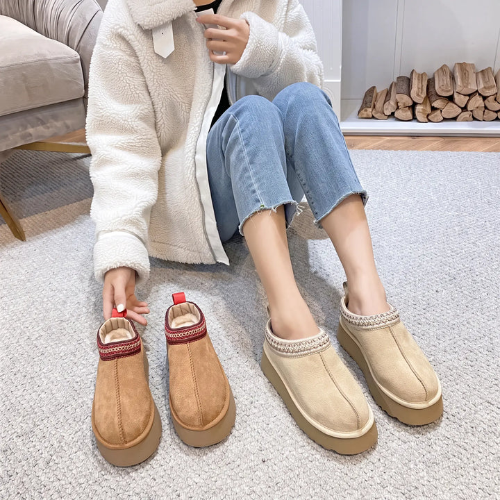 Woman wearing sand-colored cozy faux fur lined platform boots with decorative woven trim, styled with blue jeans and a white fleece jacket.