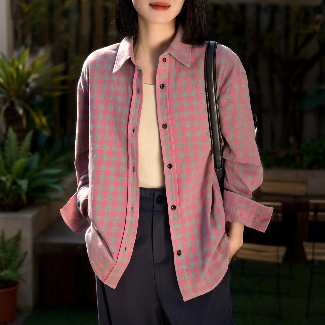A woman wears a pink and grey plaid brushed cotton shirt with a relaxed fit, paired with dark trousers. The shirt features a POLO collar and button-down front, styled casually.