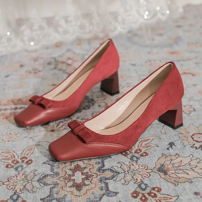 Crimson red women's square-toe pumps crafted from matte microsuede with smooth faux leather accents and a delicate bow embellishment, set on a stable chunky block heel.