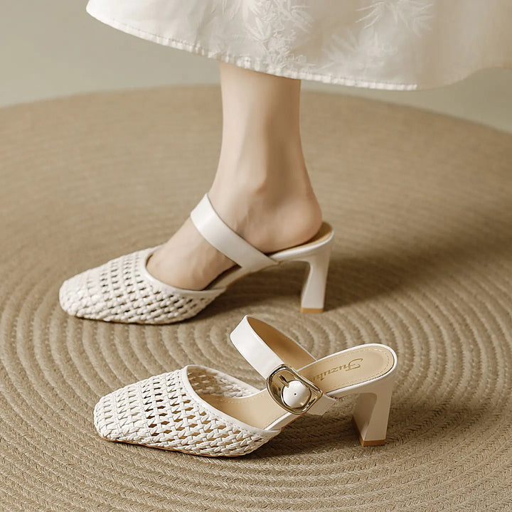 Creamy ivory woven square-toe block heel mules on a textured rug, featuring a slender ankle strap with a polished gold-tone buckle and a 7-8cm block heel.