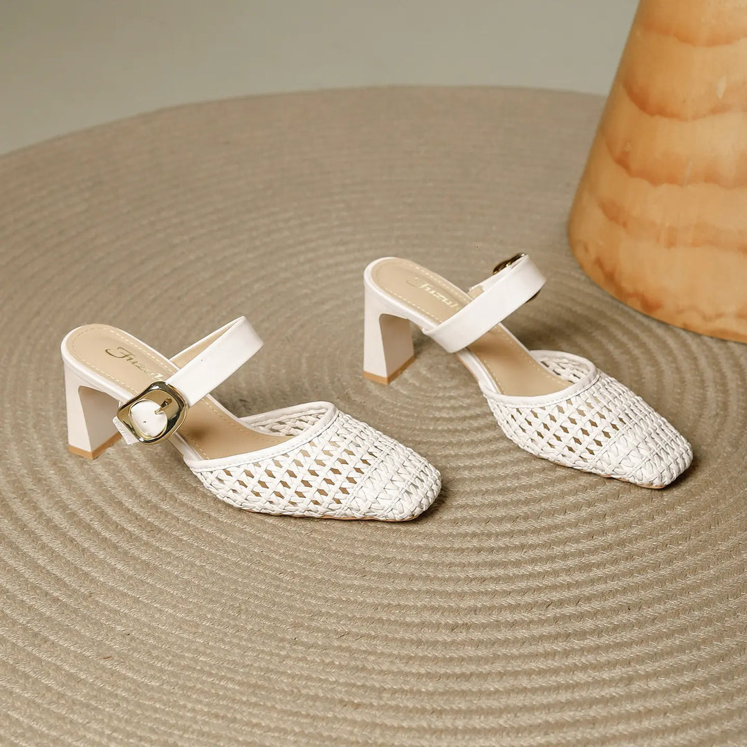 A pair of off-white woven square toe block heel mules with an ankle strap and gold buckle, shown from a three-quarter angle on a textured surface.