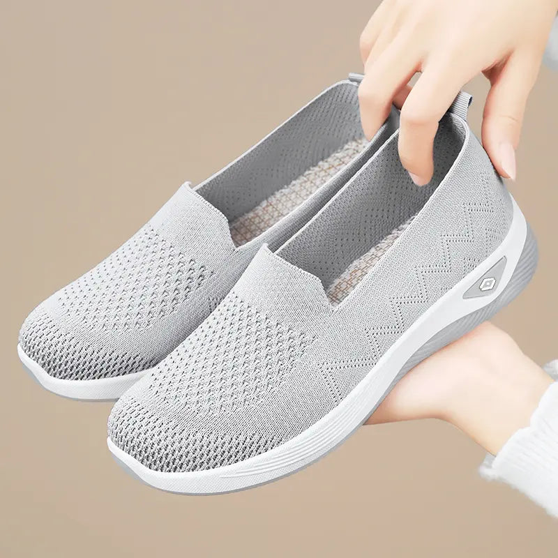 Pair of Xylo women's grey slip-on sneakers made from breathable engineered knit textile with a diamond pattern and a white sculpted sole.