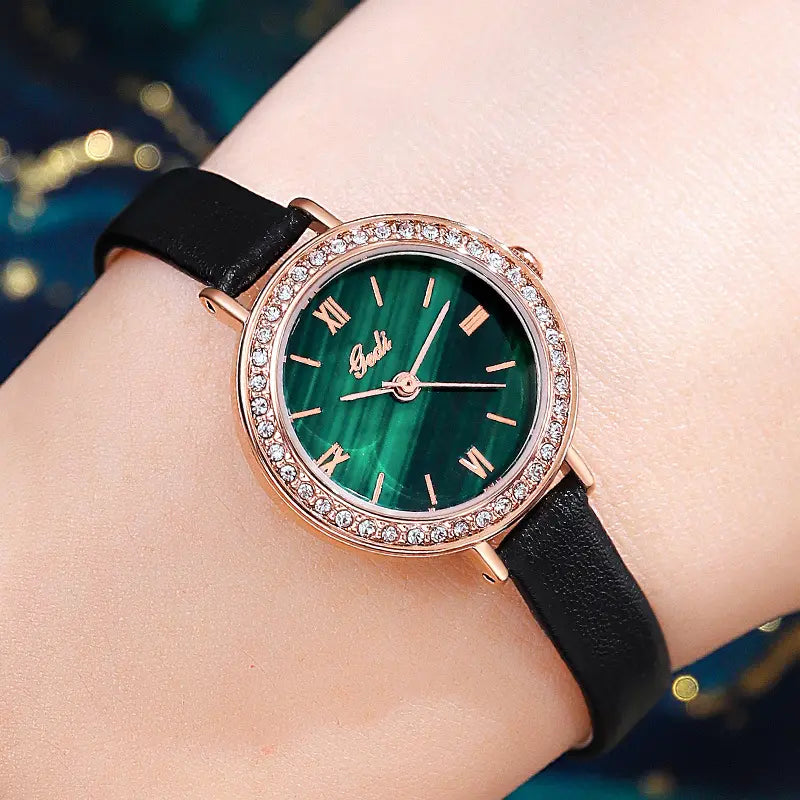 Elegant Xylos rose gold watch featuring a swirling malachite dial with Roman numerals and a sparkling cubic zirconia bezel, worn on a wrist with a slim black leather strap.