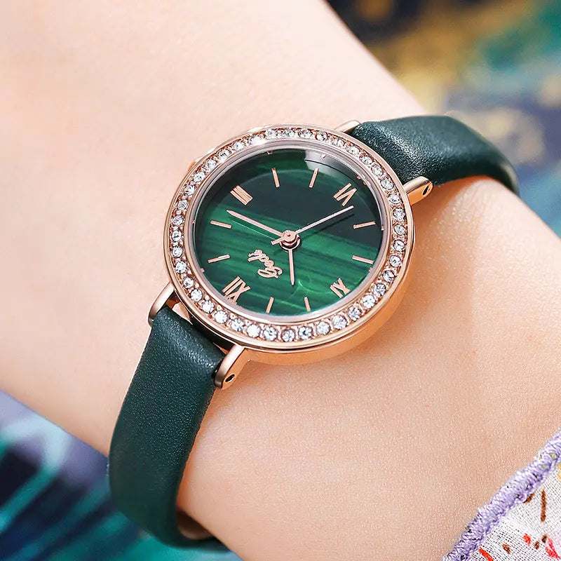 Elegant rose gold watch with a captivating malachite dial, sparkling cubic zirconia bezel, and black leather strap, shown on a woman&
