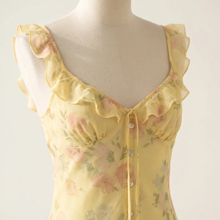Close-up of a yellow chiffon floral maxi dress featuring a plunging V-neckline with ruffled trim, adjustable tie, and delicate spaghetti straps.