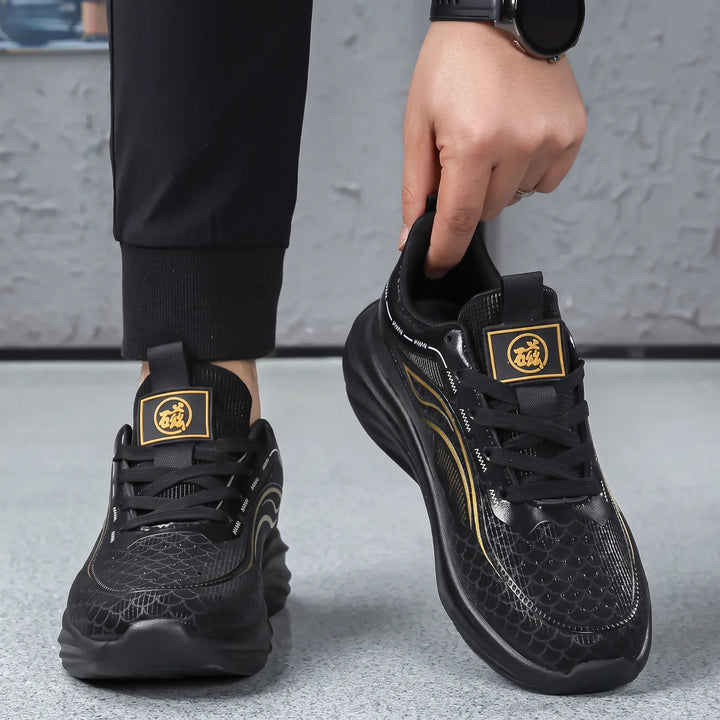Black Zephyrin performance sneakers with gold graphic accents, shown on feet with a hand adjusting the laces. These lightweight athletic shoes feature an engineered mesh upper and a sculpted sole.