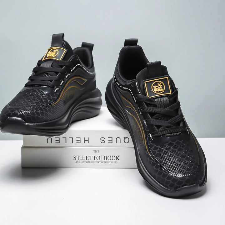 Pair of black Zephyrin lightweight performance sneakers with metallic gold accents, shown from a three-quarter view on top of books, featuring a textured upper and sculpted sole.