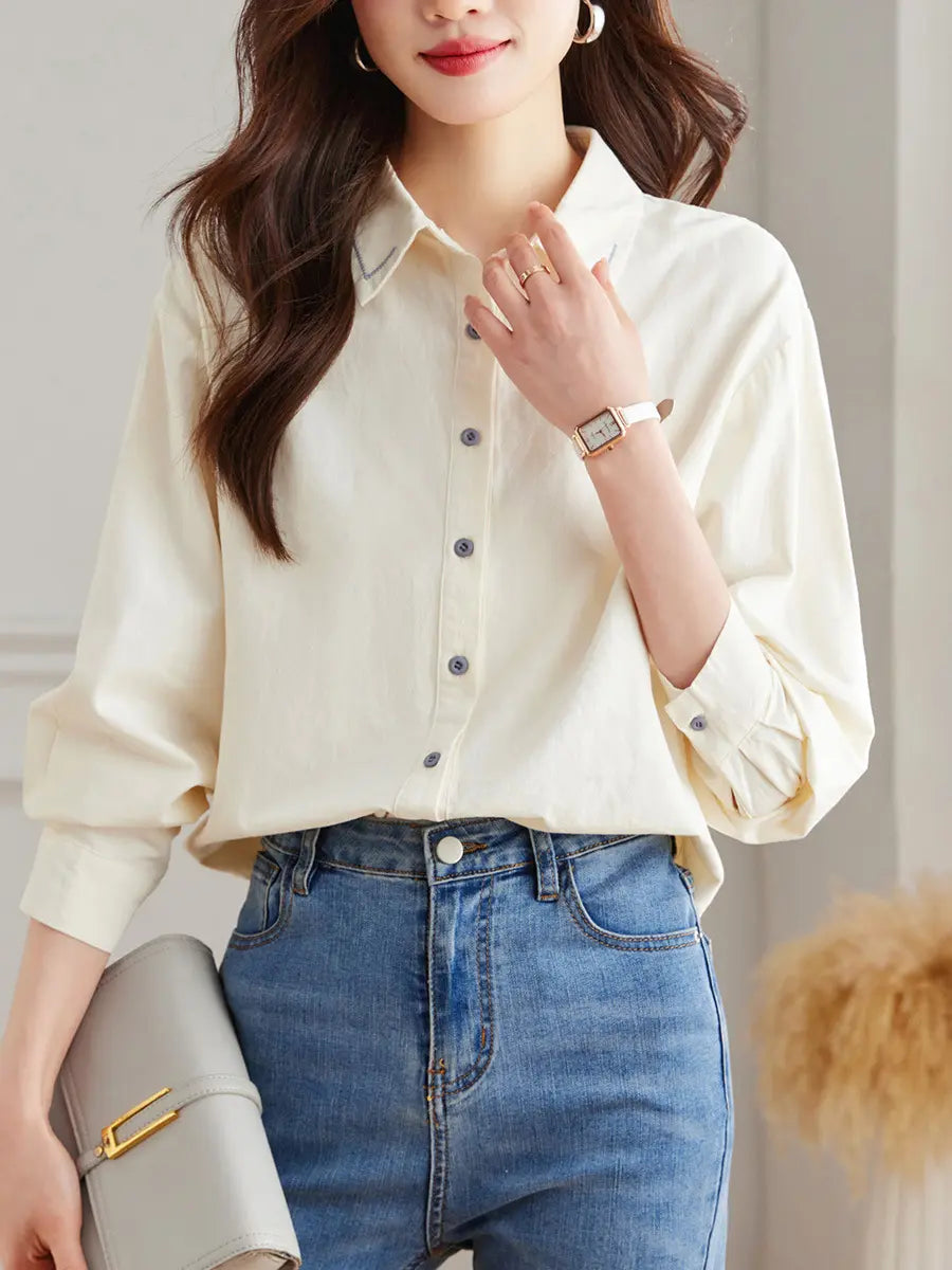 Zoryan chic embroidered cotton shirt in a muted hue, worn by a model with jeans and a clutch, showcasing the V-neck collar detail and relaxed fit.