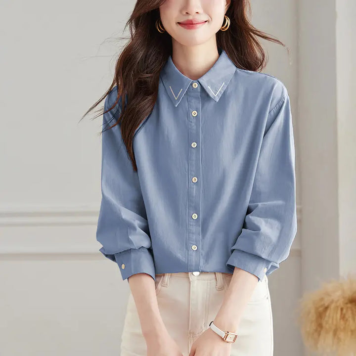 Muted sky blue long-sleeved Zoryan embroidered cotton shirt with a classic polo collar and matte button front, shown on a female model.