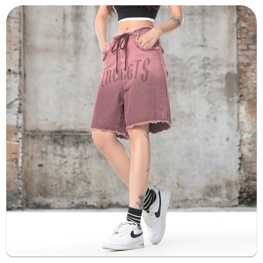 Zykra wide-leg denim shorts with distressed frayed hem, ombré wash from brown to dusty rose, and bold &