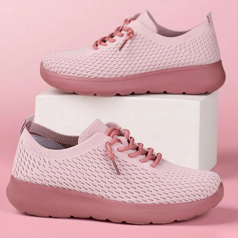 Two dusty rose knit trainers from Zylo, showcasing a three-quarter view with a seamless breathable upper and contrasting pink sole, presented against a soft pink studio background.