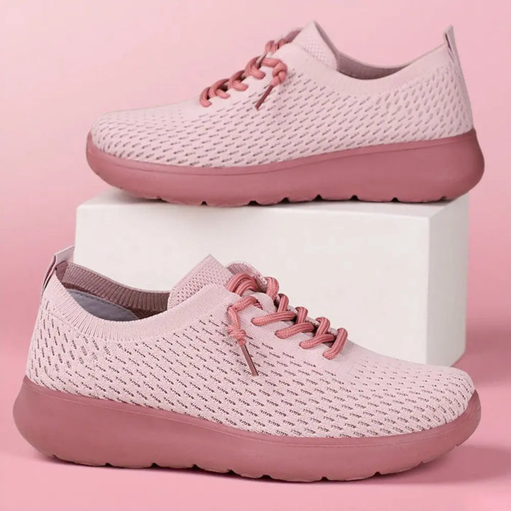 Two dusty rose knit trainers from Zylo, showcasing a three-quarter view with a seamless breathable upper and contrasting pink sole, presented against a soft pink studio background.