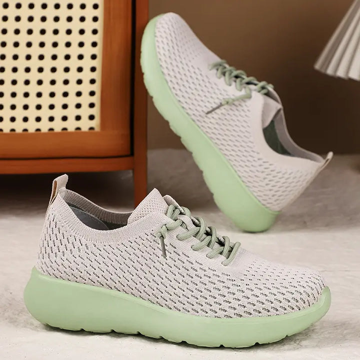 Dusty rose knit trainers with light green soles and laces, shown from a three-quarter front angle with a second shoe slightly behind against a lifestyle background.