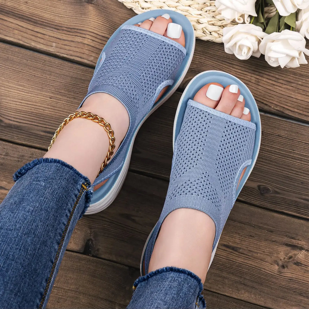 Zyloria muted dusty blue knit slip-on sandals for women, featuring an open-toe design and geometric pattern, shown in a lifestyle setting with jeans and gold anklet.
