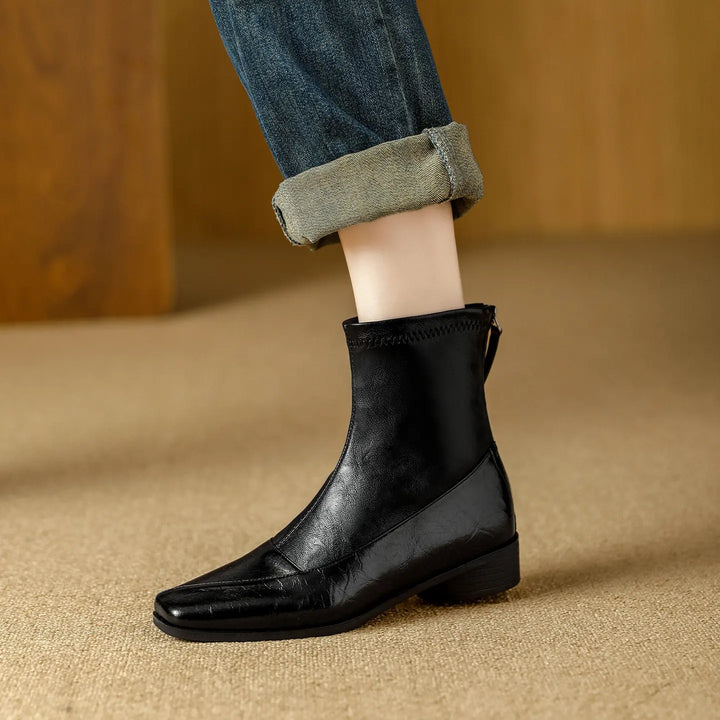 Black Zylos ankle boots featuring a chic square toe, low block heel, and rear zipper, styled with cuffed denim jeans for an elevated everyday look.