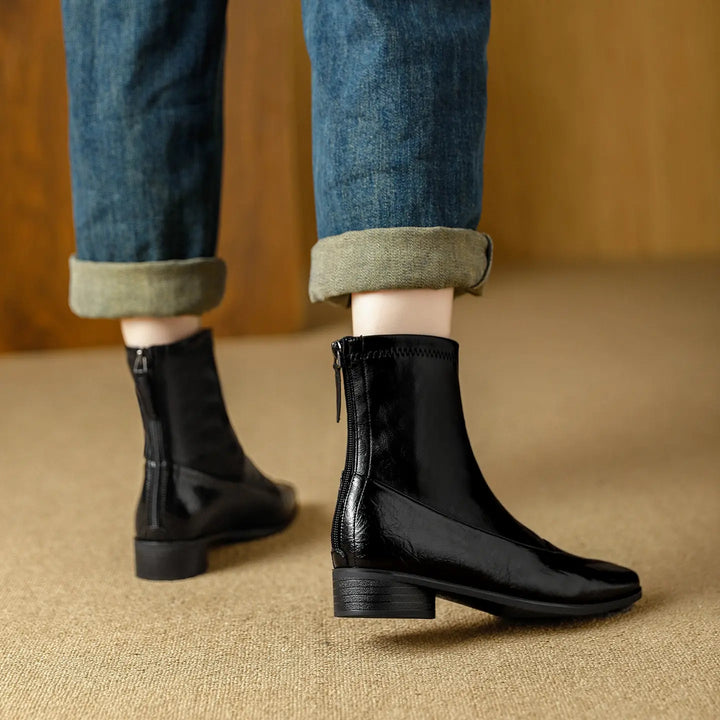 Black leather-look ankle boots with a chic square toe and stable low block heel, featuring a rear zipper and elasticated ankle, styled with cuffed blue jeans.