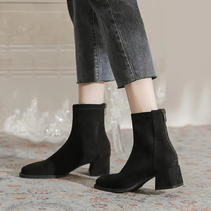 Zylos black suede-like ankle boots with a square toe and chunky block heel, worn with denim jeans. The boots feature a back zipper closure and mid-calf shaft.